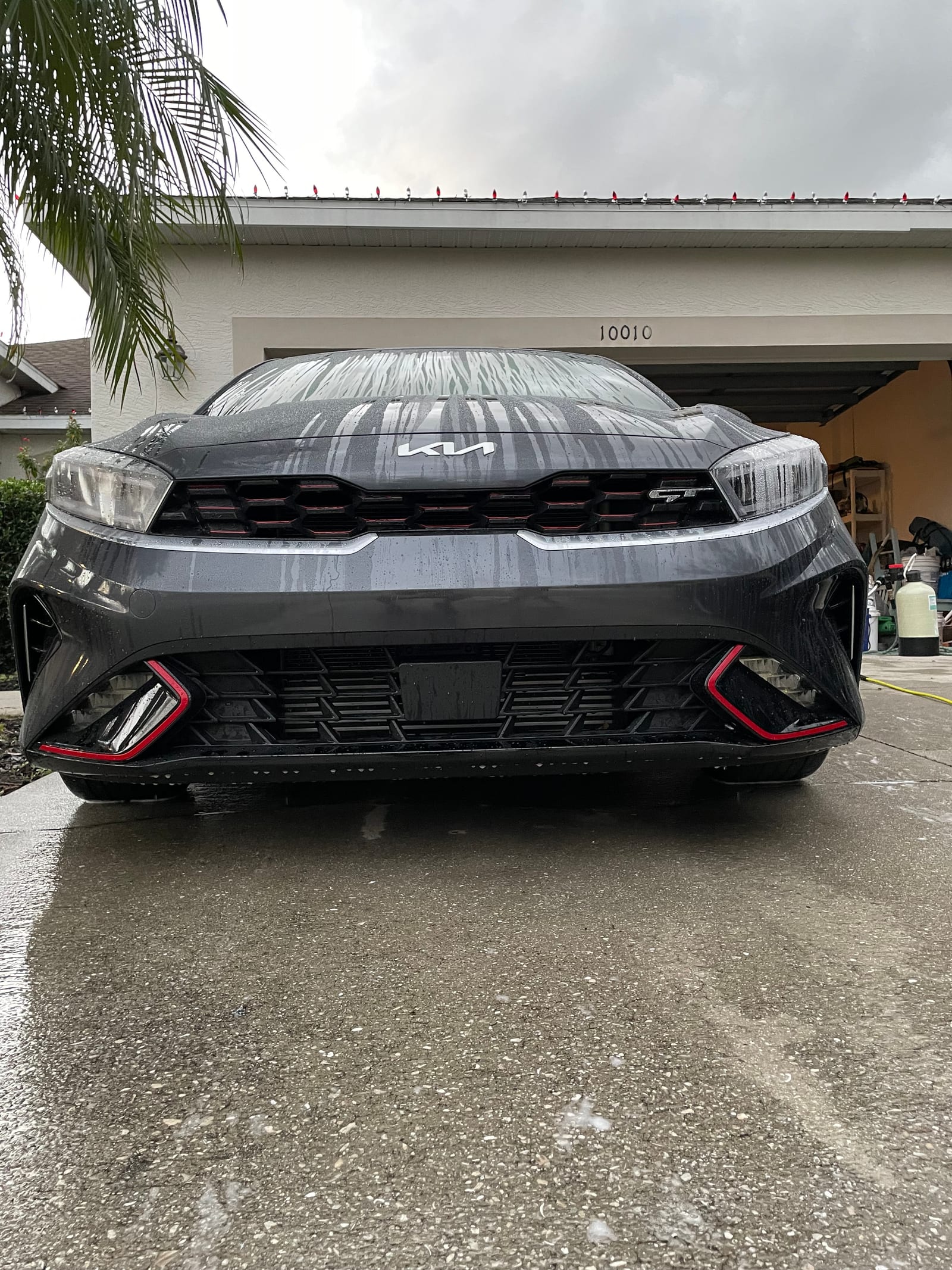 Gray Kia Forte GT being hand washed in a Bradenton driveway